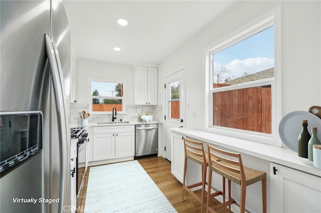 kitchen featuring plenty of natural light, appliances with stainless steel finishes, white cabinetry, and sink