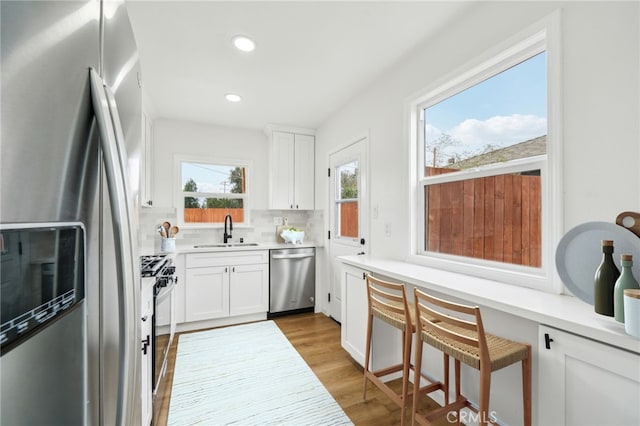 kitchen with a wealth of natural light, white cabinets, appliances with stainless steel finishes, and sink