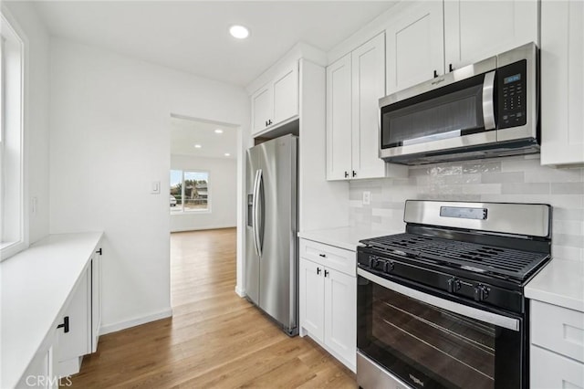 kitchen with stainless steel appliances, light hardwood / wood-style floors, white cabinets, and tasteful backsplash