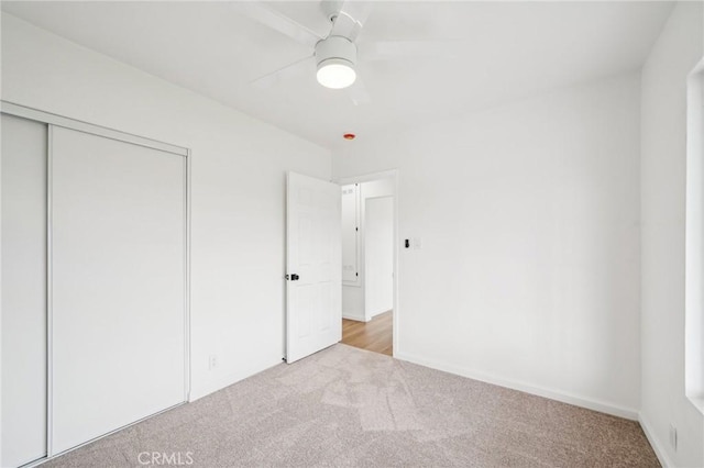 unfurnished bedroom with ceiling fan, a closet, and light colored carpet