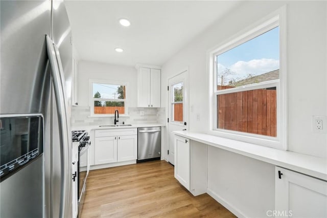 kitchen with stainless steel appliances, backsplash, white cabinets, and sink