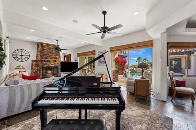 miscellaneous room with ceiling fan, beam ceiling, and a stone fireplace