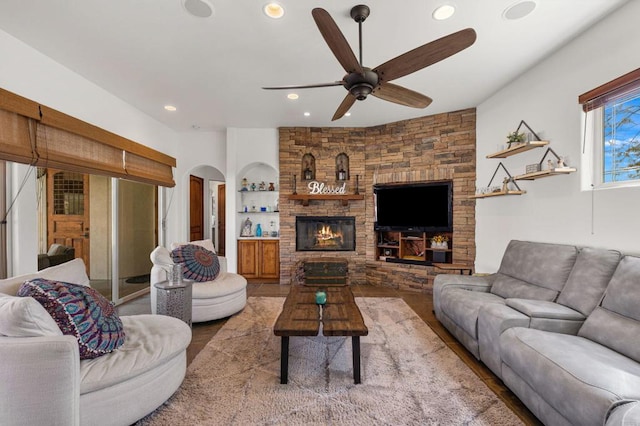 living room featuring ceiling fan, built in features, and a fireplace