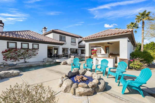 back of property with a patio area, an outdoor fire pit, an outdoor kitchen, and ceiling fan