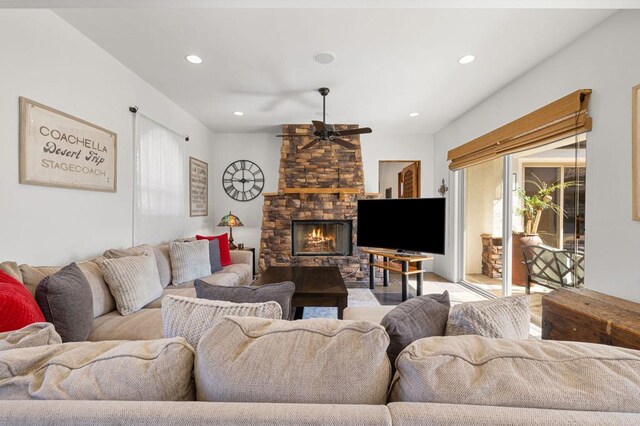 living room with ceiling fan, a healthy amount of sunlight, and a stone fireplace