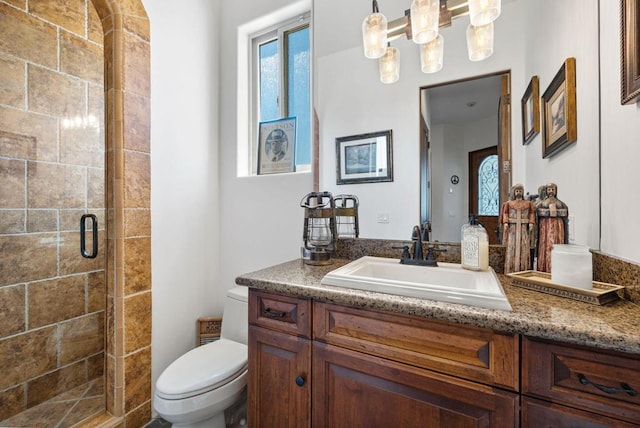 bathroom with toilet, vanity, and a shower with door