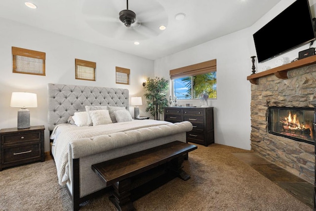 carpeted bedroom with ceiling fan and a fireplace