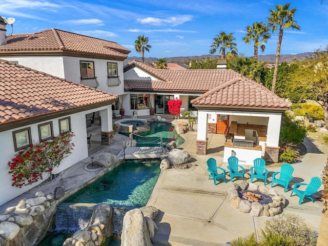 rear view of property with a pool with hot tub, an outdoor fire pit, and a patio area