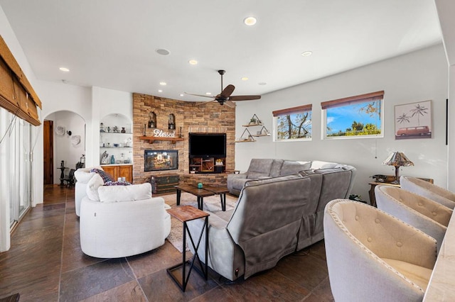 living room featuring ceiling fan, built in shelves, and a fireplace