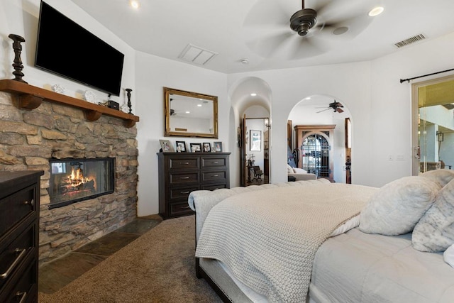 bedroom featuring ceiling fan, ensuite bath, and a fireplace