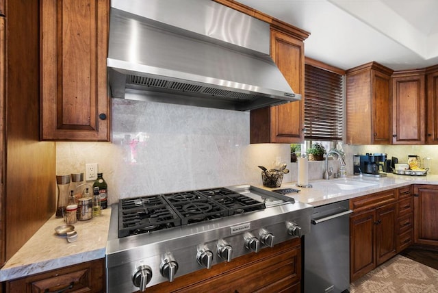 kitchen with wall chimney range hood, tasteful backsplash, stainless steel gas cooktop, light stone countertops, and sink