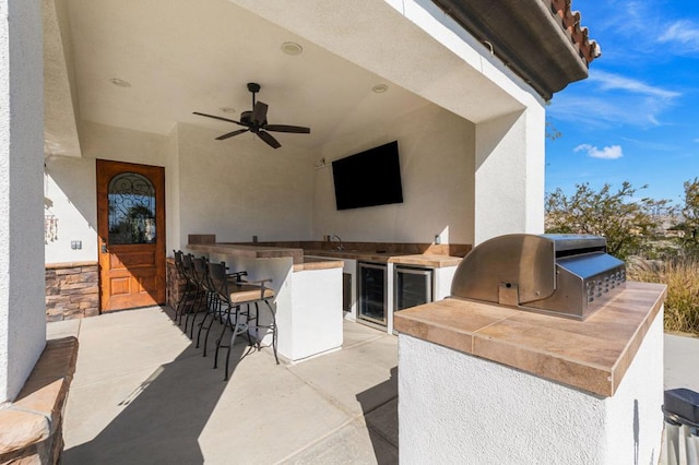 view of patio / terrace with an outdoor wet bar, ceiling fan, an outdoor kitchen, a grill, and wine cooler