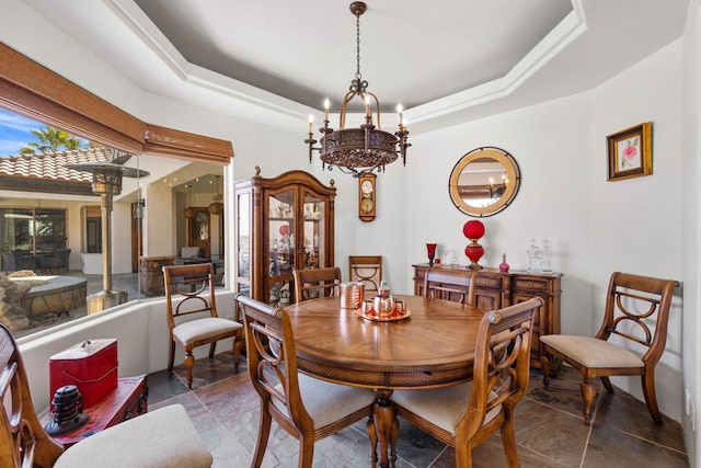 dining area with dark tile patterned floors, a tray ceiling, and a chandelier