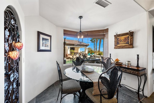 dining room with dark tile patterned floors and a chandelier