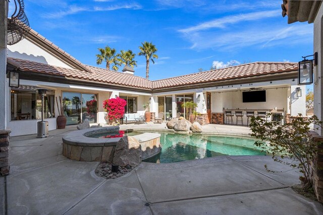 view of swimming pool with a patio, an in ground hot tub, and an outdoor bar