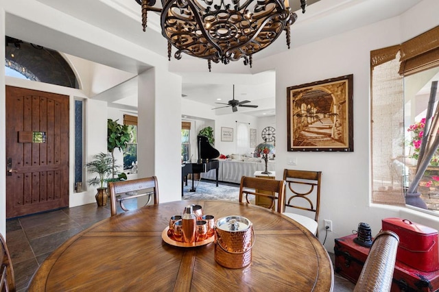 dining space featuring ceiling fan with notable chandelier