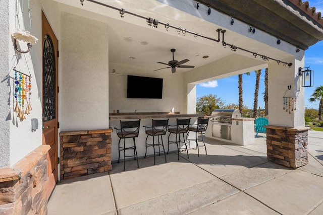 view of patio with exterior kitchen, a bar, grilling area, and ceiling fan