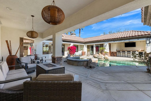 view of patio featuring a pool with hot tub, a bar, and an outdoor living space with a fire pit