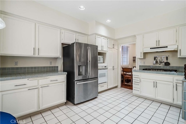 kitchen with white cabinetry, appliances with stainless steel finishes, tile countertops, and light tile patterned flooring