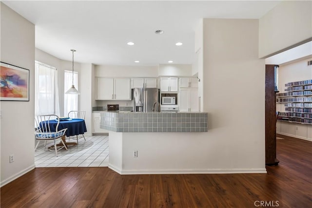 kitchen featuring decorative light fixtures, kitchen peninsula, dark wood-type flooring, stainless steel fridge with ice dispenser, and white cabinets