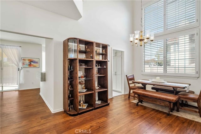 dining area featuring dark hardwood / wood-style floors, a towering ceiling, and an inviting chandelier