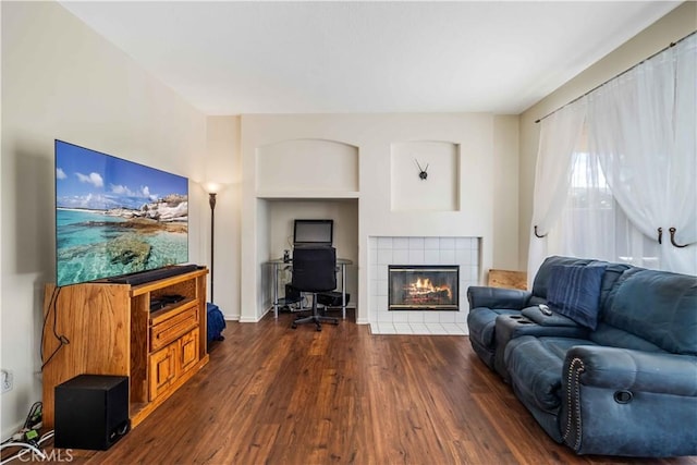 living room featuring dark wood-type flooring and a tile fireplace