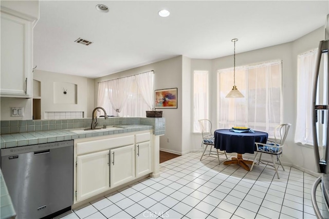 kitchen with tile counters, white cabinets, dishwasher, and sink