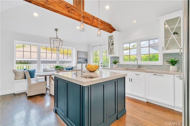 kitchen featuring beam ceiling, white cabinets, hanging light fixtures, and sink