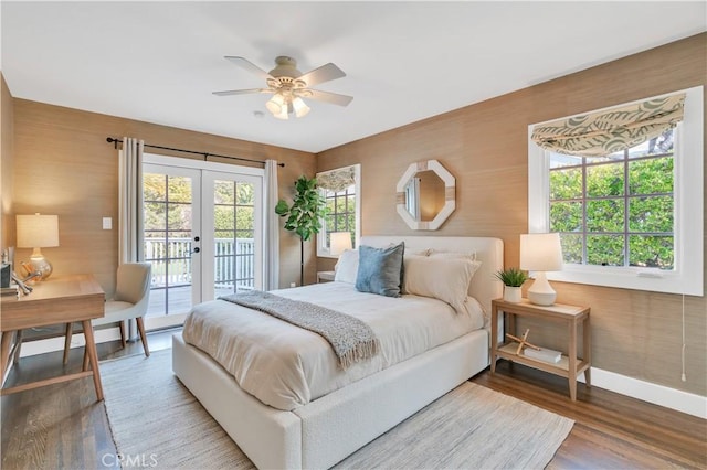 bedroom featuring hardwood / wood-style flooring, wooden walls, ceiling fan, access to exterior, and french doors