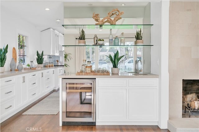 bar featuring sink, white cabinets, beverage cooler, and light hardwood / wood-style flooring