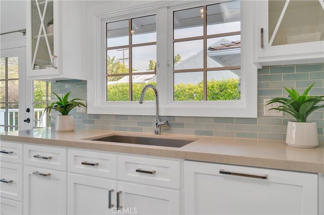 bar featuring tasteful backsplash, white cabinets, and sink