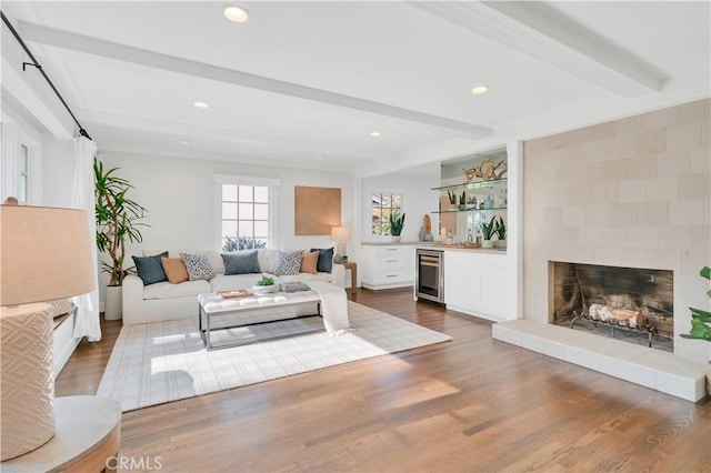 living room with dark wood-type flooring, a large fireplace, beverage cooler, and beamed ceiling