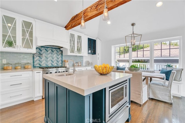 kitchen featuring white cabinets, tasteful backsplash, sink, hanging light fixtures, and stainless steel microwave