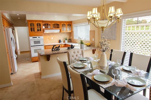 carpeted dining room featuring a healthy amount of sunlight and a chandelier