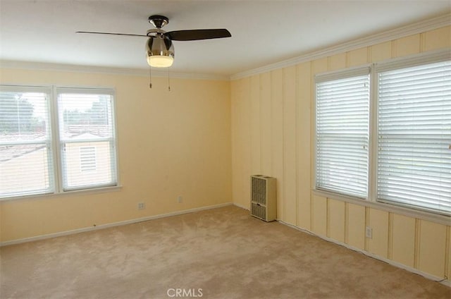 carpeted spare room featuring ornamental molding, heating unit, and ceiling fan