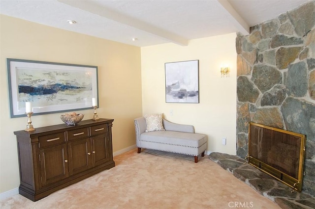 living area featuring beamed ceiling, a fireplace, and light carpet