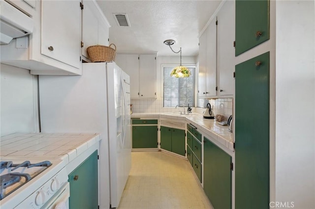 kitchen with decorative light fixtures, white cabinetry, white gas stove, tile countertops, and green cabinets