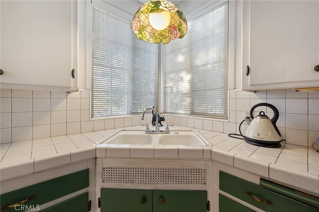 interior space featuring tile counters, white cabinets, tasteful backsplash, and sink