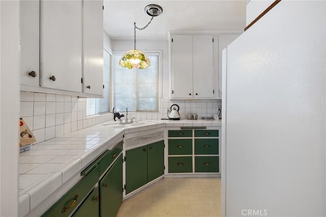 kitchen featuring green cabinets, tile counters, white cabinets, and sink