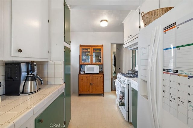 kitchen with tile counters, backsplash, white appliances, and white cabinetry