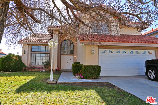 mediterranean / spanish house featuring a garage and a front yard