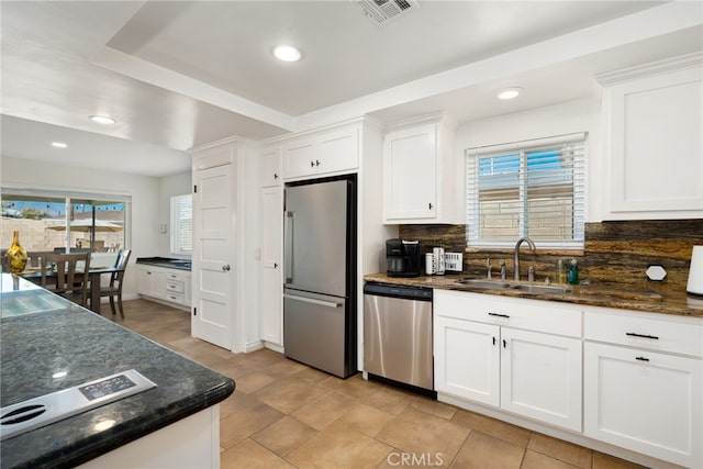 kitchen featuring white cabinets, appliances with stainless steel finishes, decorative backsplash, sink, and a raised ceiling