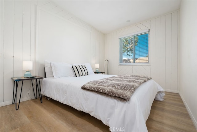 bedroom with light hardwood / wood-style floors and wood walls