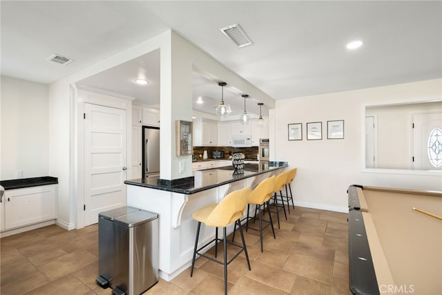 kitchen with hanging light fixtures, a kitchen breakfast bar, stainless steel appliances, white cabinets, and pool table