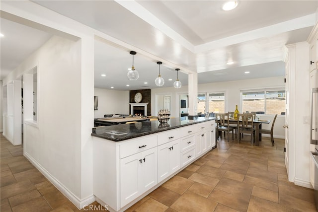 kitchen featuring dark stone counters, white cabinetry, and pendant lighting