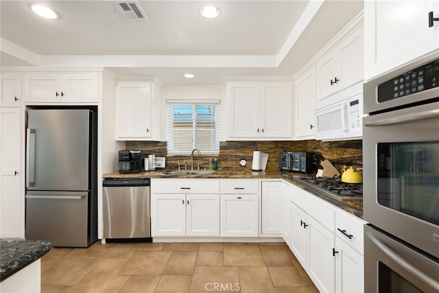 kitchen with sink, white cabinetry, stainless steel appliances, and dark stone countertops