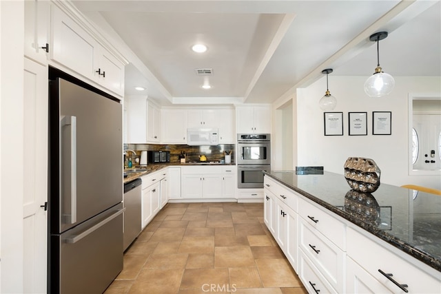 kitchen with backsplash, pendant lighting, stainless steel appliances, white cabinets, and dark stone counters