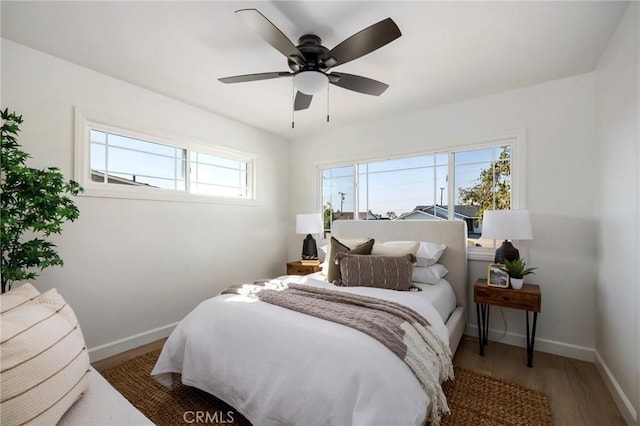 bedroom with ceiling fan, wood-type flooring, and multiple windows