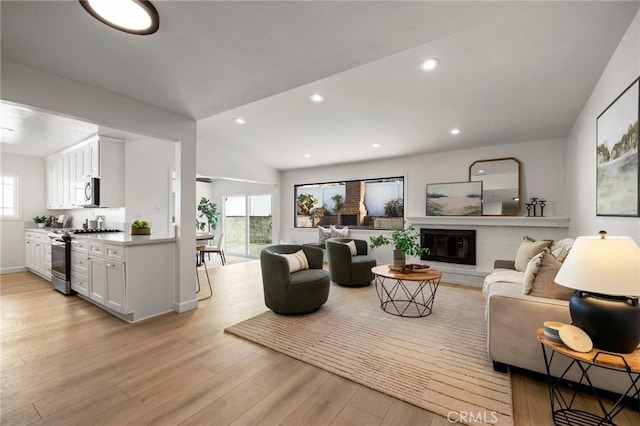 living room featuring a wealth of natural light, lofted ceiling, and light wood-type flooring