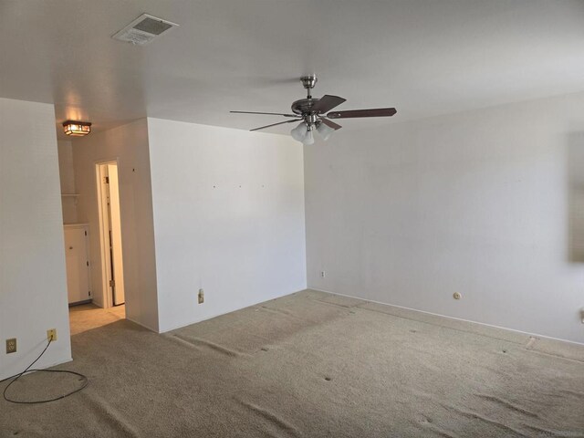 empty room featuring ceiling fan and light carpet